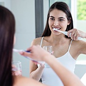 Woman brushing teeth is doing her part to prevent dental emergencies.