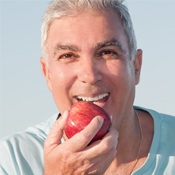 Smiling older man from Broken Arrow loves implant dentistry since he can now bite an apple.